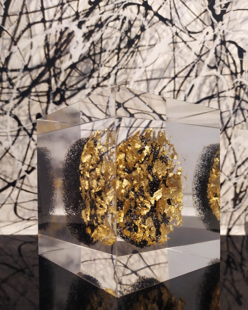 Cube avec formes en paillettes noires et feuille d'or superposées